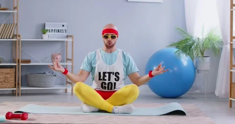 Cheerful eccentric man meditating funny and breathing deeply while sitting on 스톡 동영상 279232383