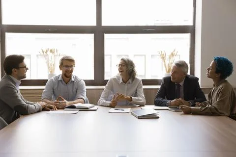 Cheerful elder and younger work colleagues discussing creative ideas Foto stock