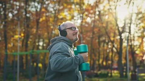 A cheerful elderly man dancing with dumbbells in his hands. Active pensioner Stock Footage 255294976