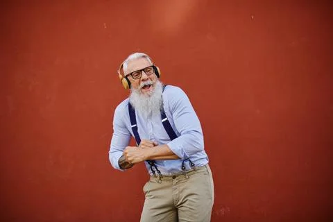 Cheerful elderly man dancing while listening to music from headset Stock Photos