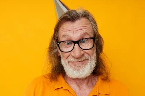 Cheerful elderly man in glasses with a cap on his head yellow background Stock Photos