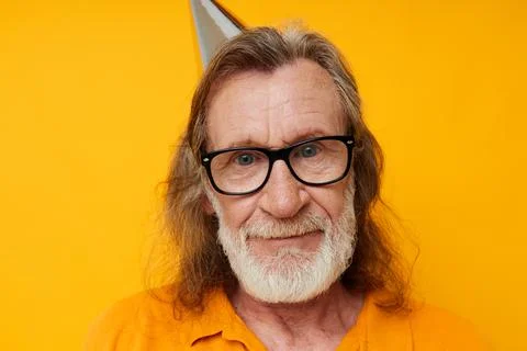 Cheerful elderly man in glasses with a cap on his head yellow background Stock Photos