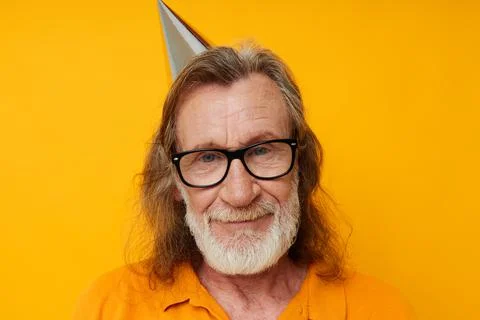 Cheerful elderly man in glasses with a cap on his head yellow background Stock Photos