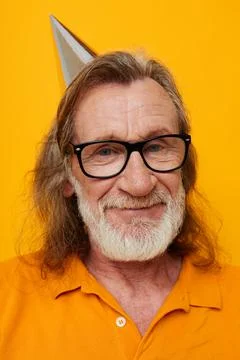 Cheerful elderly man in glasses with a cap on his head yellow background Stock Photos