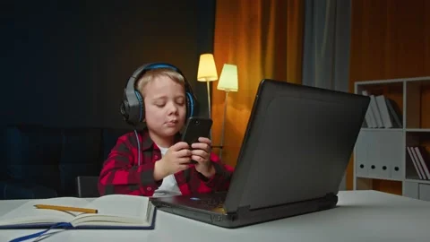 Cheerful energetic little boy using smartphone and laptop and listening to music Stock Footage 169688518