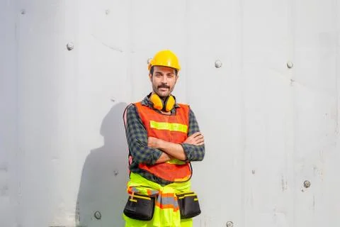 Cheerful engineer man in hard hat smiling with arms crossed Stockfoto's