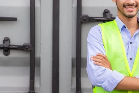 Cheerful engineer man in hard hat with arms crossed at cargo container Фото