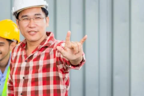 Cheerful engineer man in hard hat showing hand in I love you sign Фото