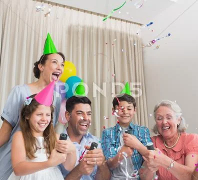 Cheerful extended family playing with Christmas crackers Stock Photos