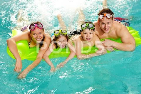 Cheerful family in swimming pool smiling at camera Stock-Fotos