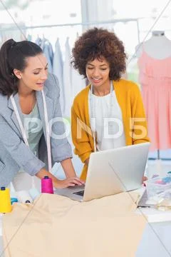 Cheerful fashion designers working on a laptop Stock-Fotos