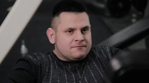 Cheerful fat man performs a wrong exercise in the gym. For the first time in a Stock Footage 105942599