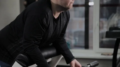 Cheerful fat man performs a wrong exercise in the gym. For the first time in a Stock Footage 105942918