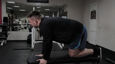 Cheerful fat man performs a wrong exercise in the gym. For the first time in a Stock Footage 105943179