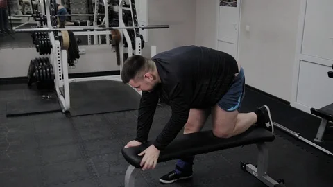 Cheerful fat man performs a wrong exercise in the gym. For the first time in a Stock Footage 105943303