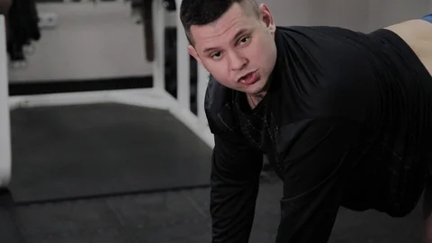 Cheerful fat man performs a wrong exercise in the gym. For the first time in a Stock Footage 105943328