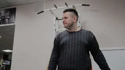 Cheerful fat man performs a wrong exercise in the gym. For the first time in a Stock Footage 105943373