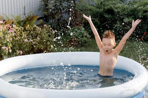 Cheerful five-year-old kid plays in the pool. funny boy splashes in an Stock Photos