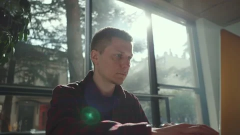 Cheerful freelancer using laptop sitting at table in cafe in sunny day Stock Footage 235365261