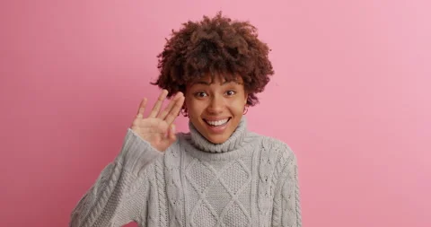 Cheerful friendly dark skinned millennial girl says hello and waves hand to Stock Footage 142747277