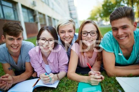 Cheerful friends lying on campus lawn Stock Photos