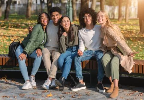 Cheerful friends posing in park while having rest in park Stock Photos