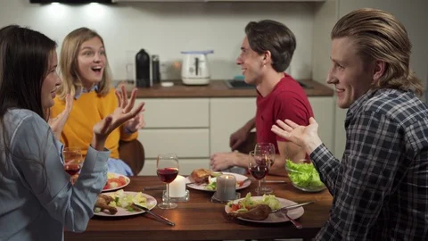 Cheerful friends talking at dinner in kitchen Stock Footage 114811333