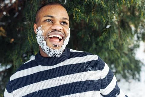 Cheerful funny African man with snow in beard enjoying winter weather Stock Photos