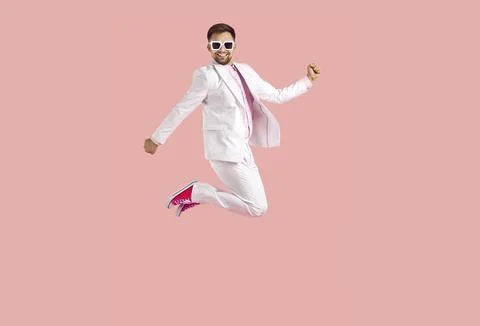 Cheerful funny young man in white suit jumps high isolated on pastel pink Stock-Fotos
