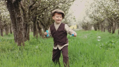 Cheerful game of the boy with soap bubbles in the garden Stock Footage 95534575