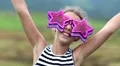 Cheerful girl in big glasses in the shape of stars looks at the camera and dance HD Footage