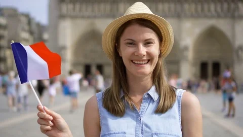 Cheerful girl enjoying vacation. Tourist in hat standing near Notre Dame of Stock Footage