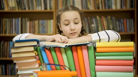 Cheerful girl laughing while reading a book in the library Stock Footage 104574416