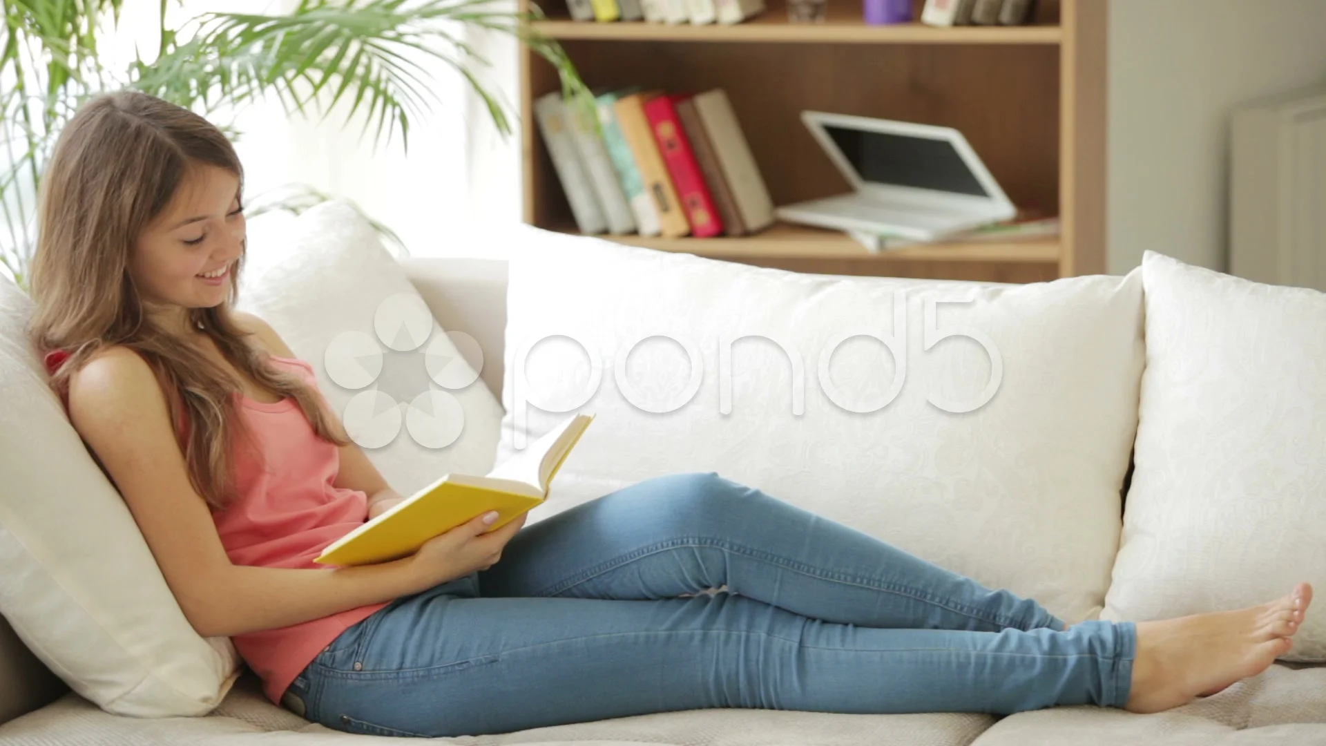 Cheerful Relaxing On Sofa Reading Book Looking At Camera And Cheerful Relaxing On Sofa Reading Book Looking At Camera And Smiling Clip 34436637