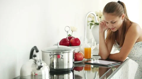 Cheerful girl standing in kitchen using touchpad looking at camera Video stock 30460530