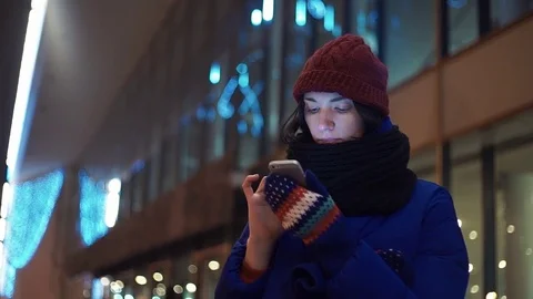 Cheerful girl texting using app on smart phone at night in city. Video stock 83071187