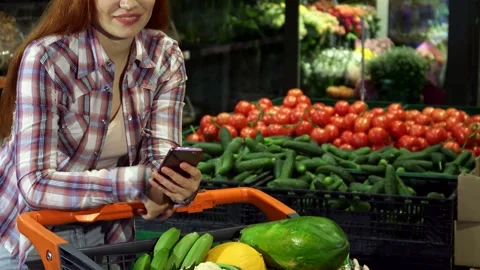 Cheerful girl using smartphone while shopping at the hypermarket Video stock 311991994
