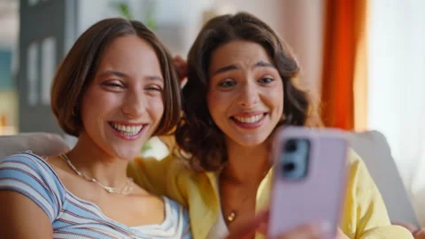 Cheerful girlfriends waving smartphone webcam having video call in home closeup. Stock Footage 333320355