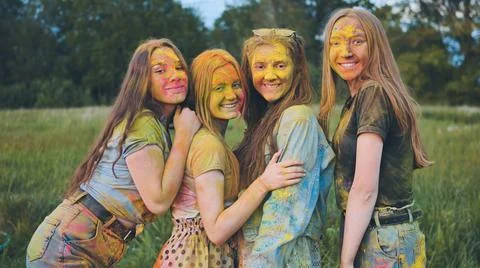 Cheerful girls posing smeared in multi-colored powder. Stock Photos