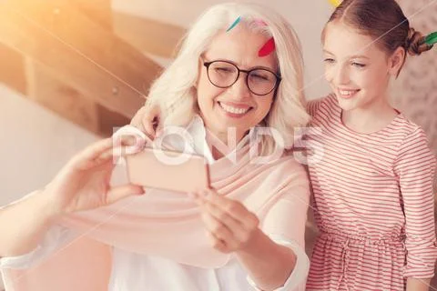 Cheerful grandmother and little girl taking selfies indoors Stock Photos