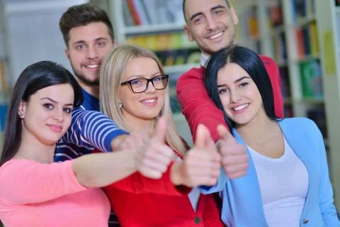 Cheerful group of students smiling at camera with thumbs up, success and Foto stock