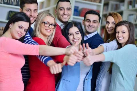 Cheerful group of students smiling at camera with thumbs up, success and Foto stock