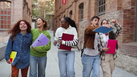 Cheerful group of students walking and laughing together while carrying colorful Stock Footage 313550298