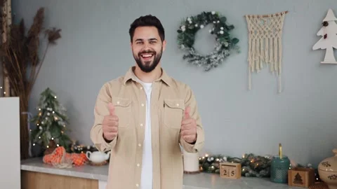 Cheerful guy in festive kitchen gives thumbs-up, signaling approval ads. 스톡 동영상 253290368