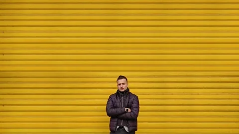 Cheerful guy in jacket poses for camera near closed shutters Stock Footage 144848483