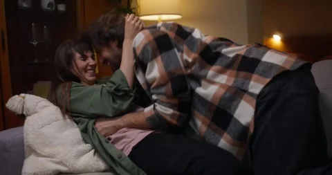 Cheerful guy plays with his girlfriend and gently squeezes her during cozy fun Stock Footage 317626809