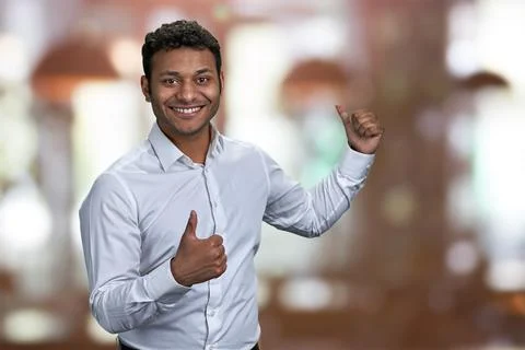 Cheerful guy pointing on copy space behind his back. Stock Photos