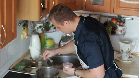 A cheerful guy preparing food in the kitchen and trying it to taste Stock Footage 86573866