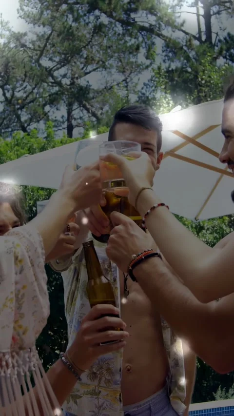 Cheerful guy raising beer bottle and friends clinking glasses poolside, boosting Stock Footage 330189512