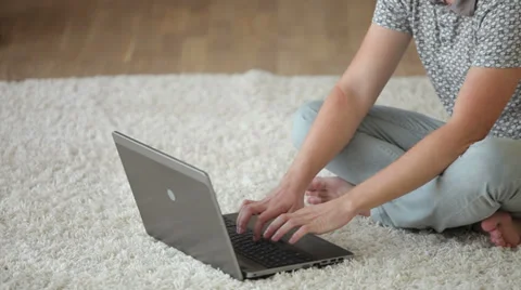 Cheerful guy sitting on floor using laptop and smiling at camera. Panning camera Stock Footage 34278125